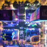 Stunning aerial view of illuminated city buildings at night with colorful lights.