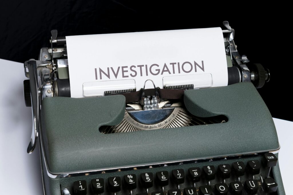A classic typewriter with the word 'INVESTIGATION' typed on paper, symbolizing mystery and retro style.