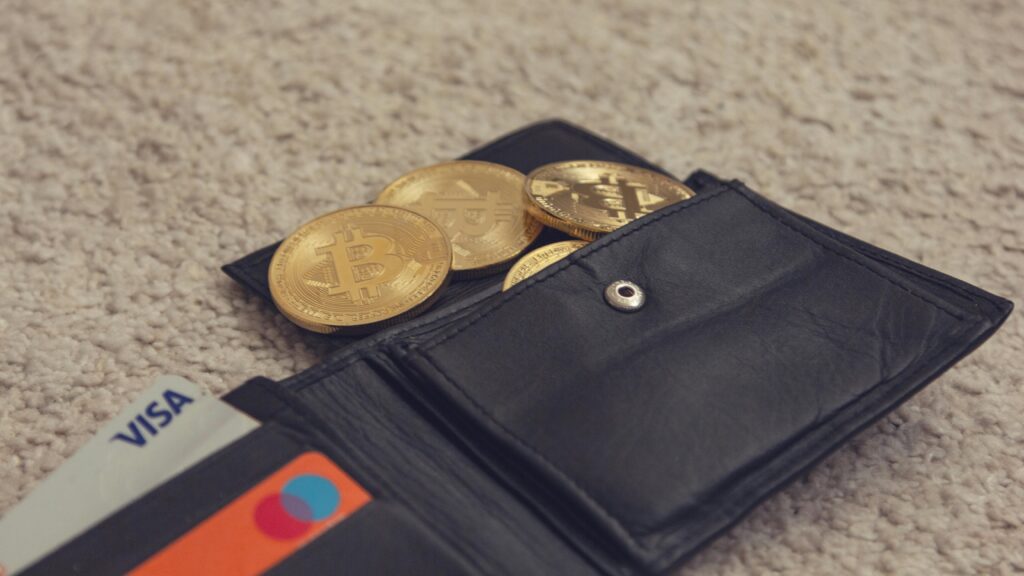 Close-up of bitcoins and credit cards inside a leather wallet, representing digital currency and finance.